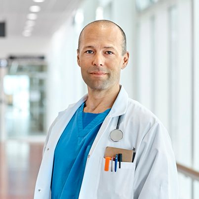 Male doctor in hospital corridor with a stethoscope and a notebook and pens in his side pocket